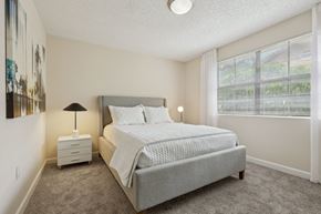 Miami apartment for rent - A bedroom with a large bed and a nightstand with a lamp.