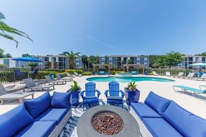 Biloxi apartment for rent - A pool area with blue couches and chairs.