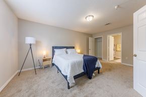 Biloxi apartment for rent - A bedroom with a bed, lamp, and carpet.