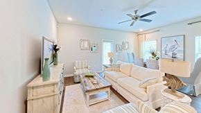 Orange Beach townhouse for rent - A living room with a white couch, a wooden cabinet, and a ceiling fan.