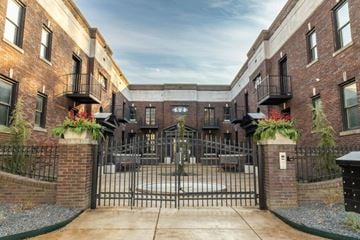 Evansville apartment for rent - A gated entrance to a brick building with a metal gate and plants on either side.
