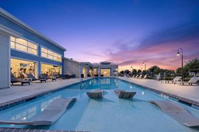 Lake Charles apartment for rent - A large indoor swimming pool with lounge chairs and a building with large windows in the background.