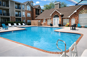 Biloxi apartment for rent - A swimming pool in front of a brick house with a white chair.