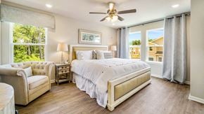 Orange Beach townhouse for rent - A bedroom with a large bed, a chair, and a ceiling fan.