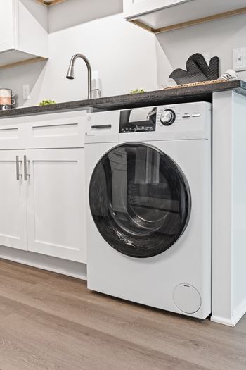 A white front loading washing machine in a kitchen