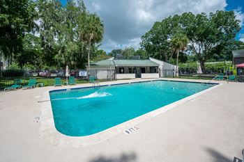 A large outdoor swimming pool surrounded by a fence and trees.