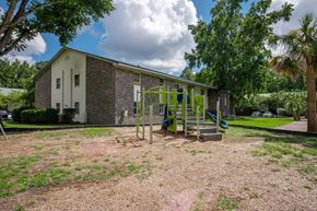North Charleston apartment for rent - A playground with a slide and swings is in front of a brick building at Brackenbrook Apartments, North Charleston