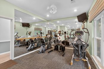 A gym with a variety of exercise equipment including treadmills, stationary bikes, and weight machines.