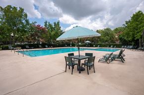 North Charleston apartment for rent - A pool with chairs and a table under an umbrella at North Bluff Apartments, North Charleston, South Carolina