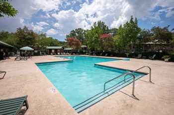 A large swimming pool surrounded by trees and a fence.