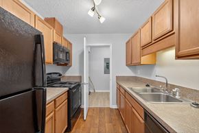 North Charleston apartment for rent - A kitchen with a black refrigerator and brown cabinets at North Bluff Apartments, North Charleston, South Carolina