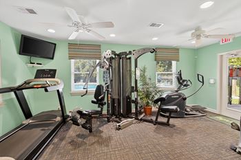 A gym with a treadmill, elliptical trainer, and a stationary bike.