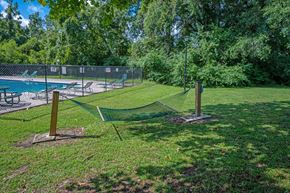 Summerville apartment for rent - A tennis court is surrounded by a fence and trees at Sawbranch Apartments, South Carolina, 29485