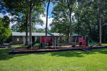 A playground with a green slide and red and green swings.