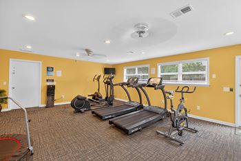 A spacious gym with a variety of equipment including treadmills, elliptical machines, and a stationary bike.