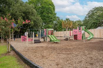 A playground with a green slide and a red slide.
