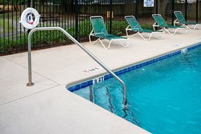 Moncks Corner apartment for rent - A pool with a metal railing and green chairs at Woodlocke Apartments, Moncks Corner, SC