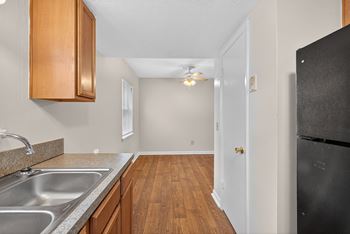 A kitchen with wooden cabinets and a black refrigerator.