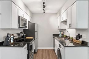 Wilmington townhouse for rent - A kitchen with white cabinets and black appliances at The Preserve at Pine Valley Apartments, Wilmington, 28412