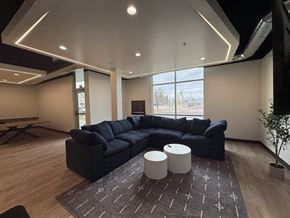 Logan apartment for rent - A black sectional sofa with a round ottoman in front of it.