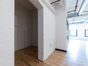 Racine apartment for rent - A white room with wooden floors and a doorway leading to another room.
