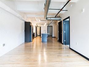 Racine apartment for rent - A long hallway with doors on both sides and a trash can in the middle.
