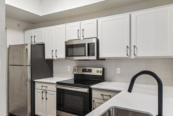 A kitchen with white cabinets and black appliances.
