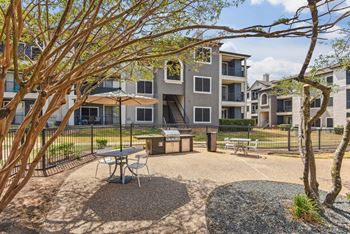 A courtyard with a picnic table surrounded by trees and apartment buildings.