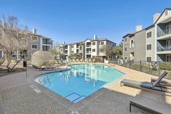 A pool surrounded by apartment buildings and a sun lounger.