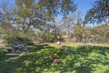 A park with a picnic table and a red object on the grass.