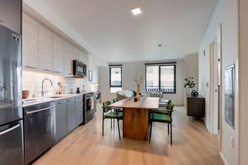 A modern kitchen with stainless steel appliances and wooden flooring.