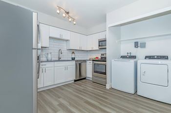 A modern kitchen with white appliances and wooden flooring.