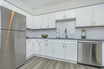 A kitchen with white cabinets and a stainless steel refrigerator.