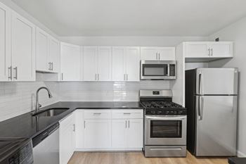 A kitchen with white cabinets and black countertops.