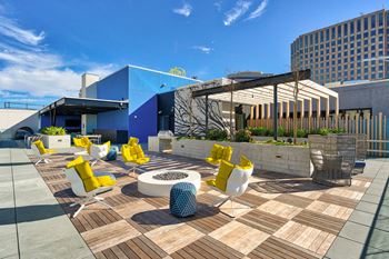 A modern outdoor seating area with yellow chairs and a white table.