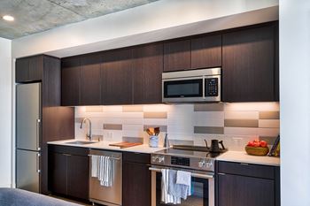 A modern kitchen with dark wood cabinets and stainless steel appliances.