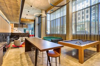 A room with a pool table and a bar area.