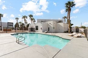 Las Vegas apartment for rent - A swimming pool in front of a house with a fence and palm trees.