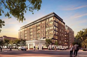 Boston apartment for rent - A modern building with a curved front is surrounded by trees and people walking on the sidewalk.