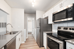 Dallas apartment for rent - A kitchen with white cabinets and black appliances.