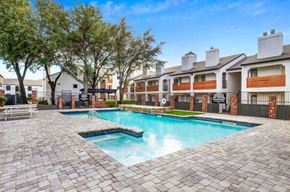 Dallas apartment for rent - A swimming pool surrounded by a brick patio and apartment buildings.