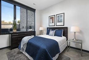Chicago apartment for rent - A bedroom with a large bed and a window overlooking the city.