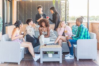 A group of people are sitting on a patio with a woman standing behind them