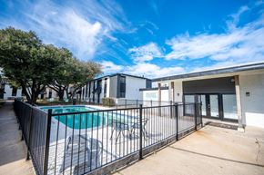 Waco apartment for rent - A pool surrounded by a black fence with a building in the background.