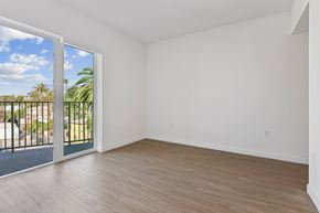Los Angeles apartment for rent - A room with a sliding glass door leading to a balcony with a view of a fence and trees.