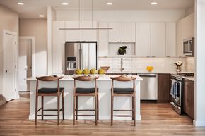 Burlington apartment for rent - a kitchen with white cabinets and a white island with three chairs