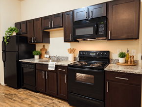 Reading apartment for rent - A black refrigerator, microwave, and oven are on a kitchen counter with brown cabinets.