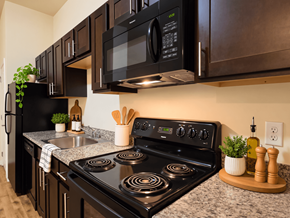 Reading apartment for rent - A black microwave is mounted above a black stove in a kitchen.