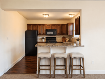 Temple apartment for rent - A kitchen with a black refrigerator, a microwave, and a counter with two stools.