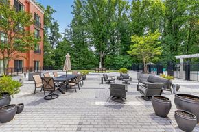 Gaithersburg apartment for rent - A patio with a table and chairs surrounded by trees.